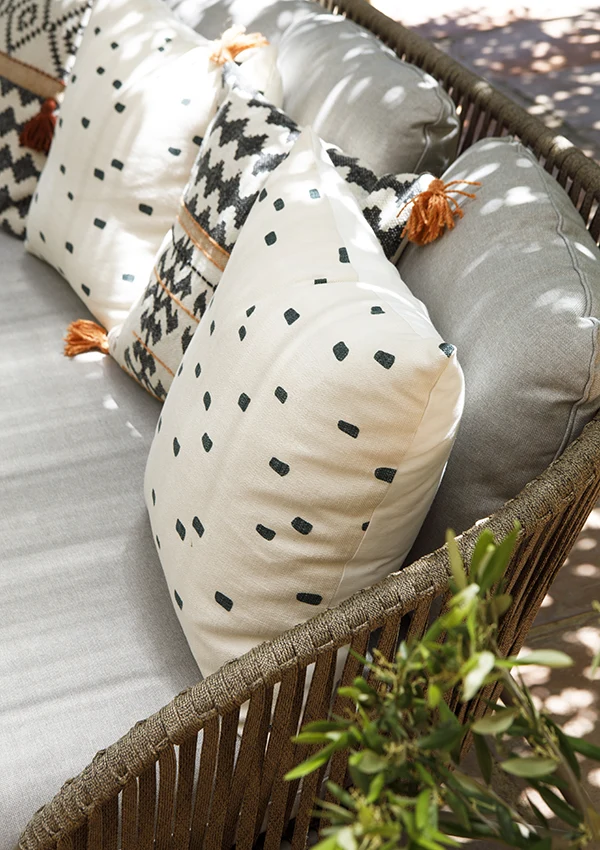 Cojines sobre sofá exterior con estampados y colores complementarios.