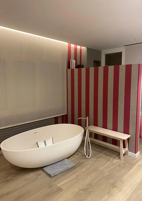 Bañera exenta con paredes a rayas rojas, anulando el espacio de relajación.