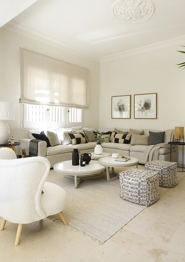 Salón con sofá en L, estor y alfombra en tonalidades similares con el resto del mobiliario.
