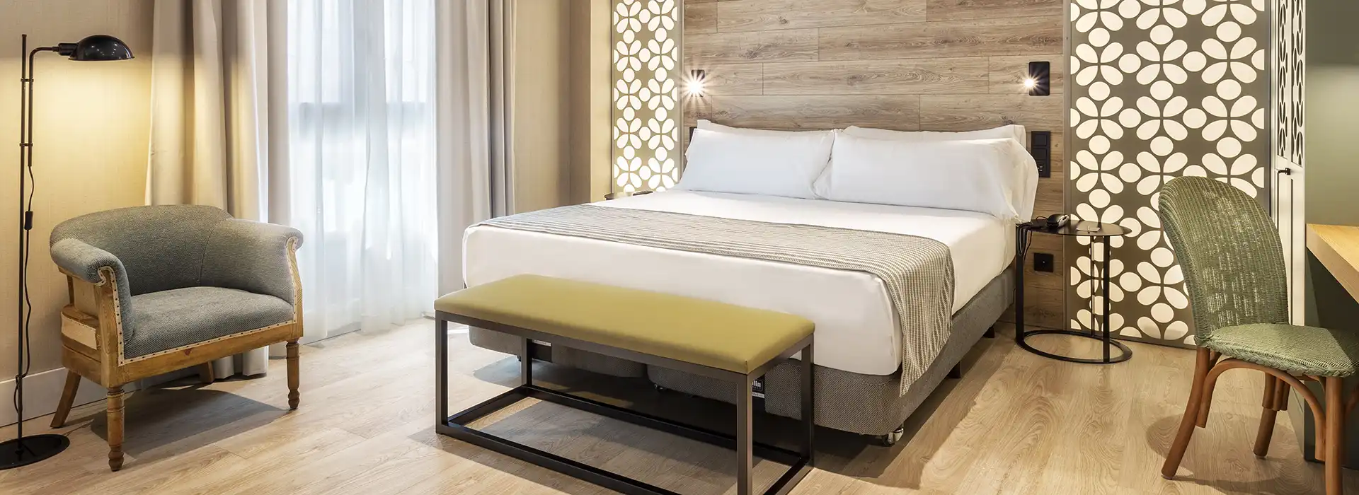 Suite de hotel con textiles en cortinas, butacas y ropa de cama.