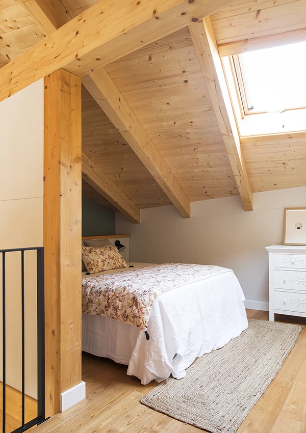 Dormitorio con cama semi-oculta, colocada en buhardilla al final de la escalera.