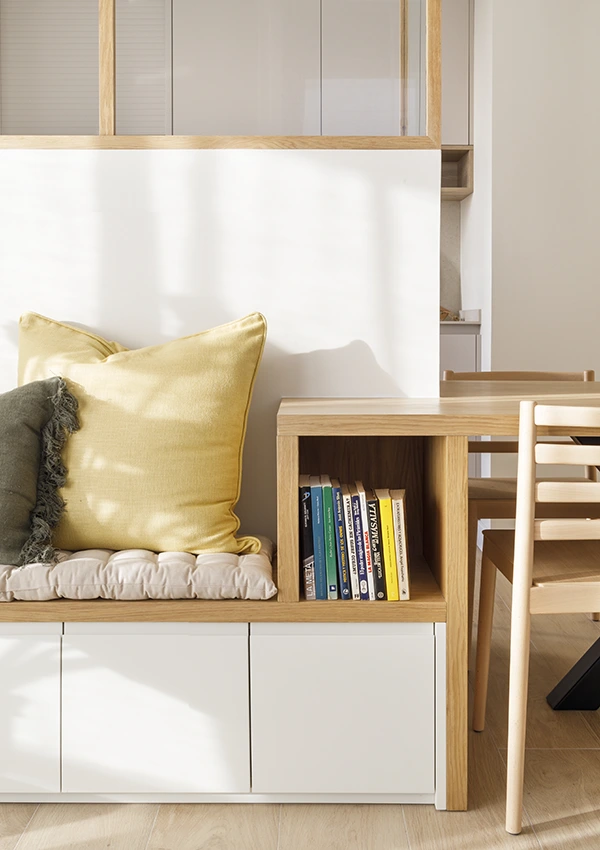 Mueble a medida apoyado en muro de separación de cocina, diseñado para sentarse y almacenar cosas en la parte inferior.