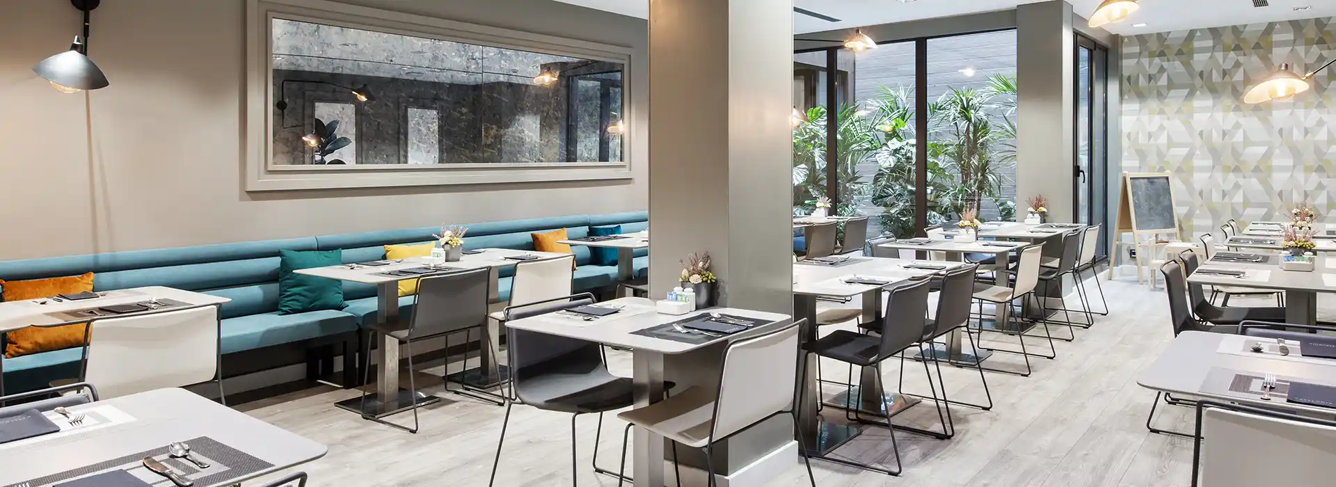 Salón de desayuno en hotel: sillas y mesas minimalistas con bancos azules.