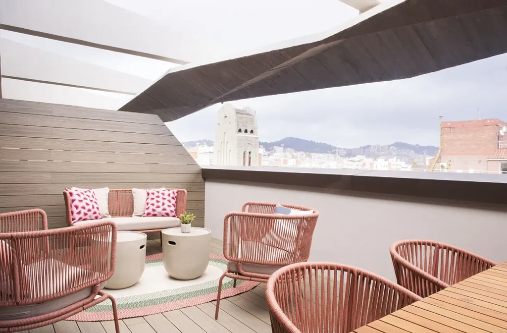 Terraza exterior con mobiliario en tonos rosas y blancos.