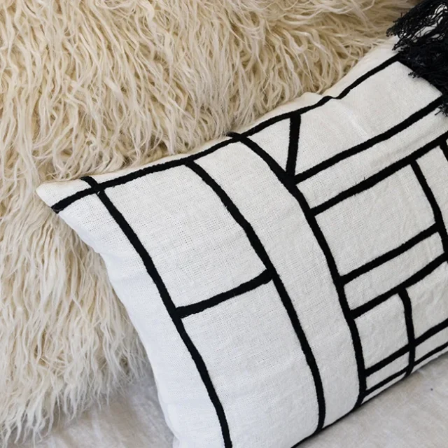 Cojines decorativos en color blanco, negro y crema.
