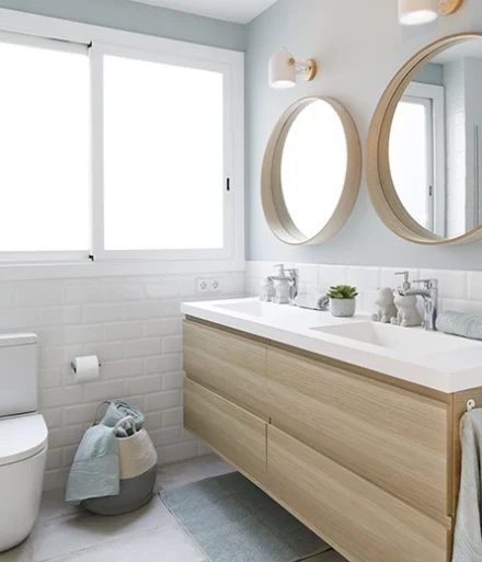 Aseo con lavabo y espejos dobles en madera clara.