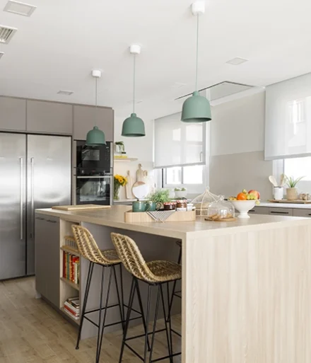 Cocina abierta con amplias encimeras y nevera doble de acero. Lámparas de techo en color turquesa.