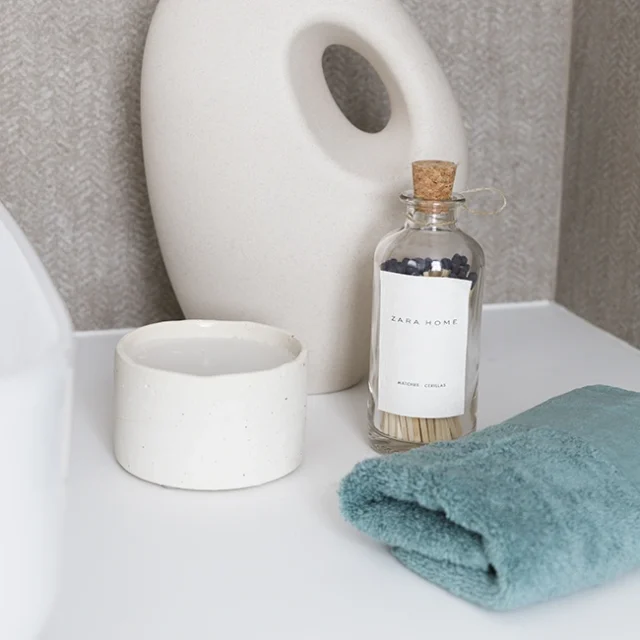 Decoración de baño: jarrón abstracto, cerillas en bote de cristal con tapón de corcho y vela de color blanco.