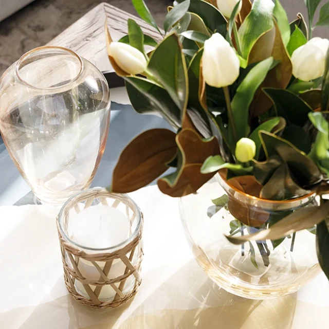 Jarrones transparentes decorativos, velas y ramo de tulipanes blancos sobre mesa de café.