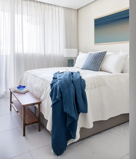 Dormitorio de matrimonio con tonos blancos y toques azul marino.