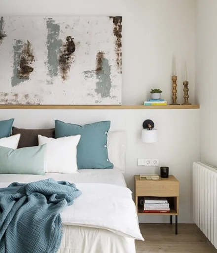 Dormitorio de matrimonio en tonos neutros y claros, con toques de color azules en cojines y mantas.