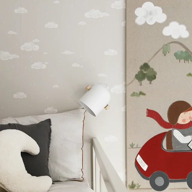 Papel de pared con nubes, a juego con cuadro decorativo, en habitación infantil.