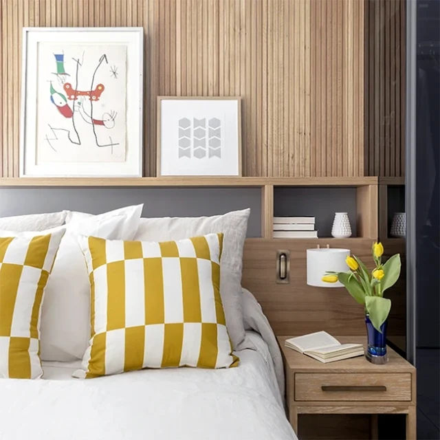 Obras de arte en cabezal de la cama, hornacinas para almacenamiento extra y decoración con toques de color amarillo.