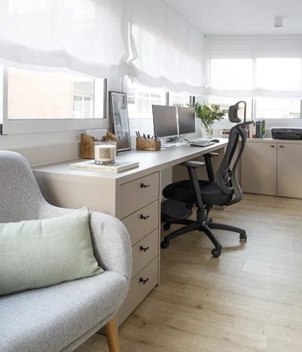 Oficina amplia con escritorio blanco y silla ergonómica.