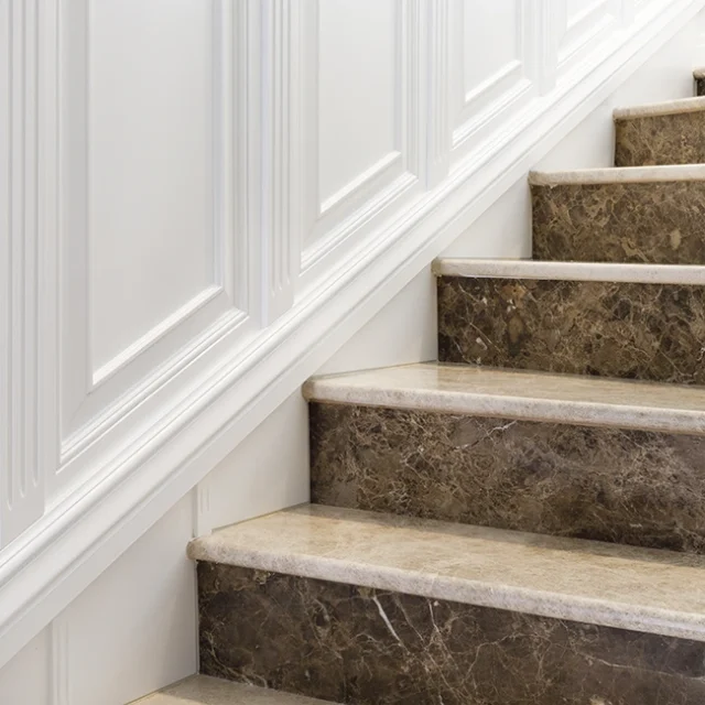Escaleras de mármol junto a pared blanca con molduras.