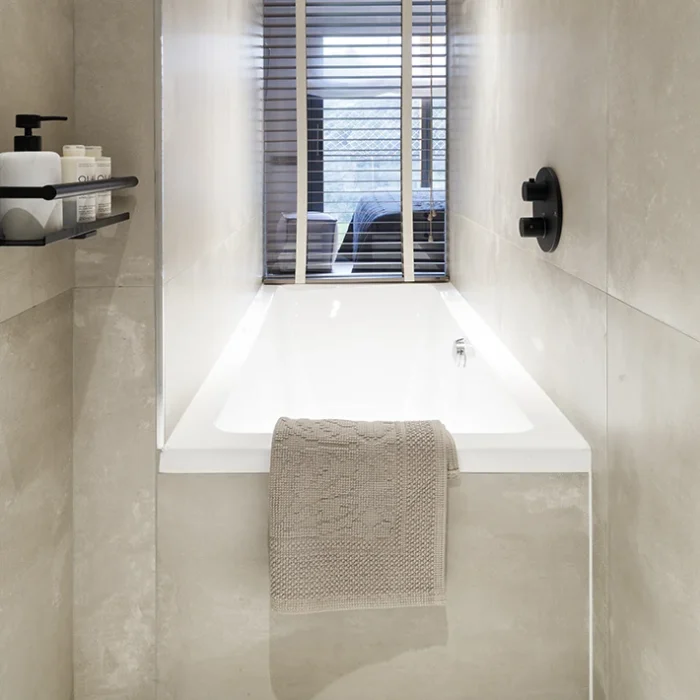 Bañera con ventana a la suite principal. Paleta de colores neutra con blancos, grises y negros.
