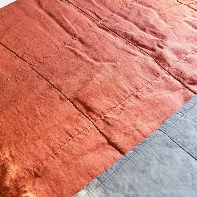 Textura de ropa de cama de color terracota y grisácea.