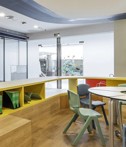 Espacio con libros educativos en estantes cerca de zonas de trabajo.